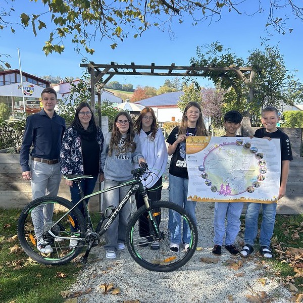 Schüler und Schülerinnen mit einem Fahrrad und einem Plakat vor der Schule