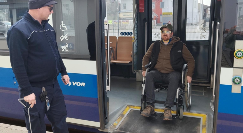 Ein Mann im Rollstuhl verlässt über eine Rampe die Straßenbahn