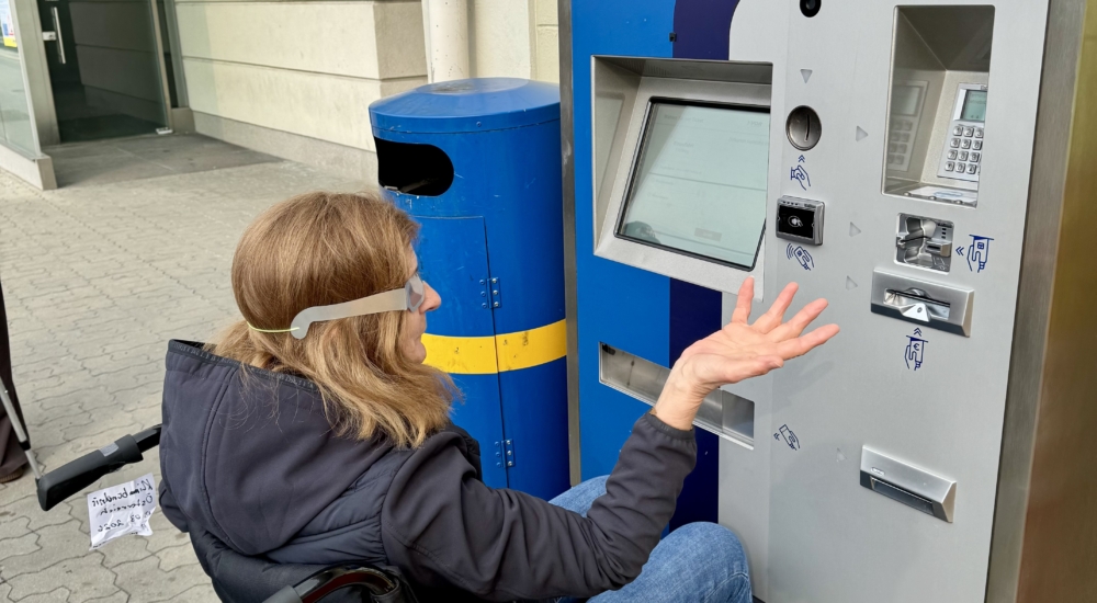 Person im Rollstuhl nutzt einen Fahrkartenautomaten