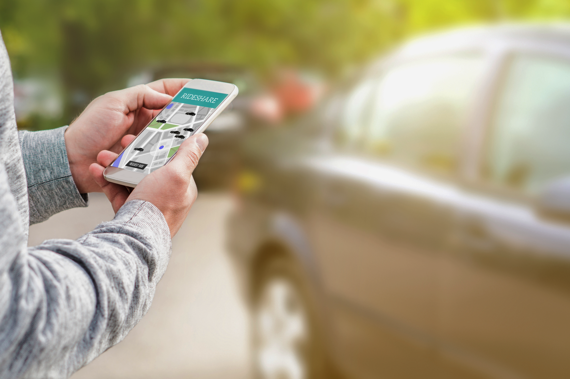 Eine Person hät ein Handy in der Hand, auf dem Display sieht man eine Kartenapp mit Autos